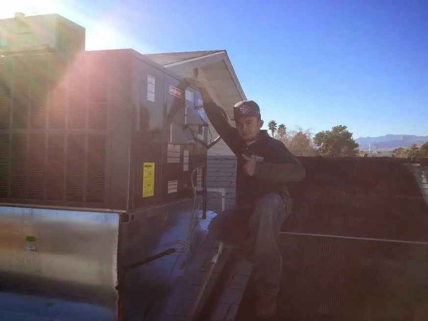 HVAC technician performing Air Duct Cleaning on a rooftop unit in Leisure City